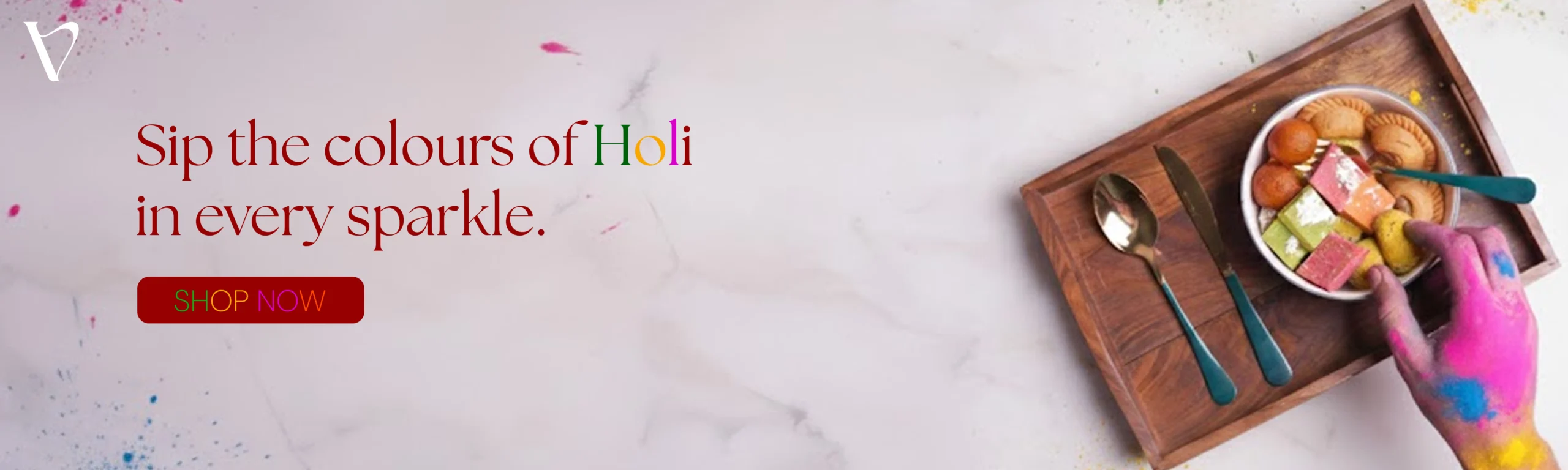 Celebrate Holi with festive essentials. Banner showing a wooden serving tray filled with gujiya and sweets on a marble background with color splashes.